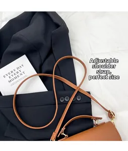 Detail of brown lychee grain handbag featuring adjustable strap on black blazer