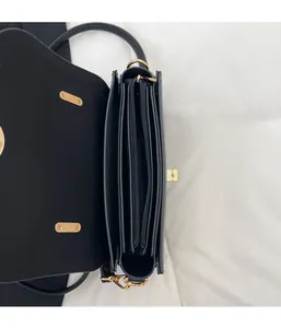 Détails d'un sac à bandoulière noir avec plusieurs compartiments internes et zips dorés