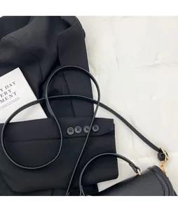 Close-up of black lychee grain leather texture with stitching and adjustable shoulder strap