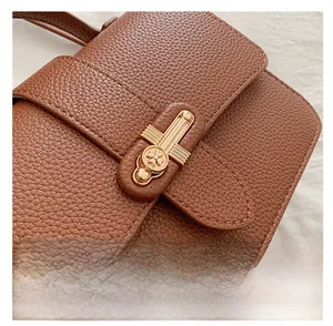Detailed macro view of dark brown lychee textured leather and clover embossed gold clasp