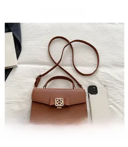 Gros plan du sac à main en cuir marron avec nœud décoratif et smartphone pour échelle