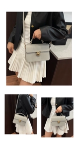 Close-up of a gray leather handbag with litchi texture and golden round lock buckle
