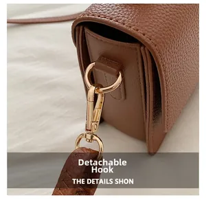 Detail shot of the golden detachable hook on a brown litchi pattern leather bag