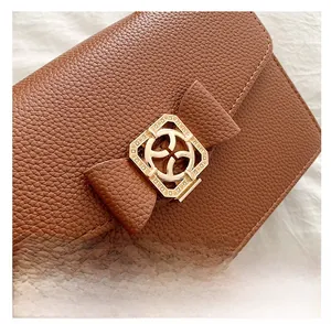 Gros plan du sac à main en cuir marron avec boucle carrée dorée et détail de nœud en cuir