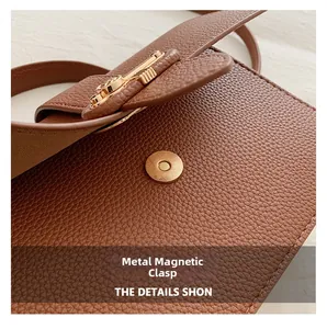 Detail of golden magnetic clasp on brown litchi textured leather handbag