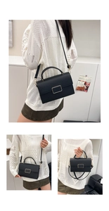 Detail view of black lychee texture crossbody bag with gold buckle and top handle strap