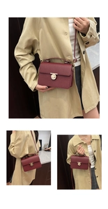 Detail of burgundy pebbled leather handbag featuring a golden circular twist-lock clasp