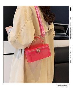 Detail of pink translucent jelly vanity bag with wide logo strap on beige coat