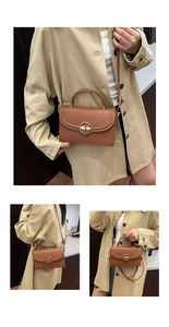 Detailed close-up of brown grain leather handbag with gold circular metal lock buckle