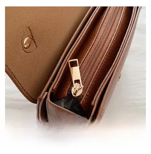 Detail view of the smooth golden zipper and lychee pattern brown leather texture