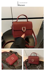 Detailed view of the maroon pebbled leather square bag with a golden U-shaped buckle