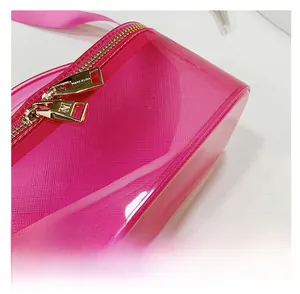 Close-up of golden dual zippers with Marc Eliza logo on pink PVC crossbody bag