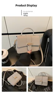Detail view of light grey litchi texture leather handbag with metal buckle and strap