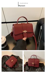 Detail of burgundy crossbody bag with lychee pattern texture and gold metal buckle