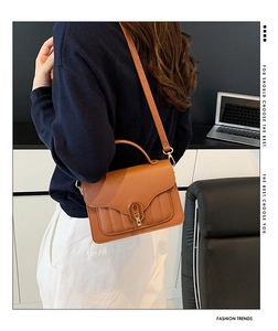 Détail du sac à main marron caramel en cuir texturé avec fermoir en métal doré sur modèle