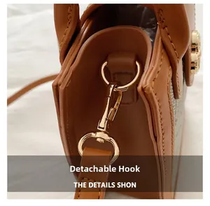Detail of the golden detachable spring hook hardware on a caramel brown leather bag