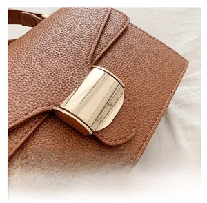 Gros plan d'un sac à main marron en cuir grainé avec un fermoir métallique doré courbé