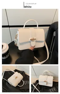 Detail of white litchi pattern leather bag with golden cross buckle and shoulder strap