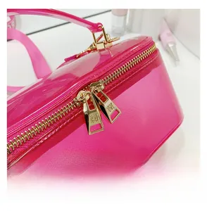 Detail of pink translucent cosmetic bag featuring a golden double zipper and cross texture