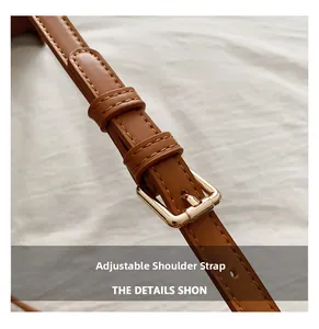 Close-up of brown leather adjustable shoulder strap with golden metal buckle and stitching