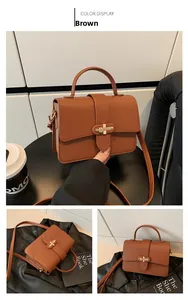 Detail view of brown lychee grain leather handbag with gold metal bar lock and top handle