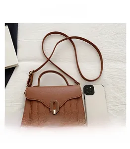 Détail du sac en cuir marron avec fermoir en bronze comparé à un smartphone moderne