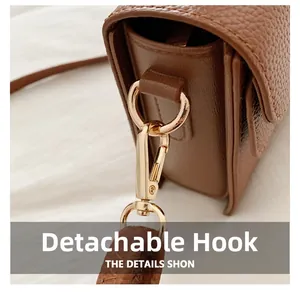 Detail view of the detachable gold-tone lobster hook on brown lychee leather bag