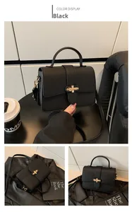 Detail view of black lychee grain faux leather handbag with golden cross lock closure