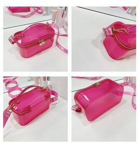 Detail view of glossy pink jelly box bag with wide logo strap and gold metallic hardware