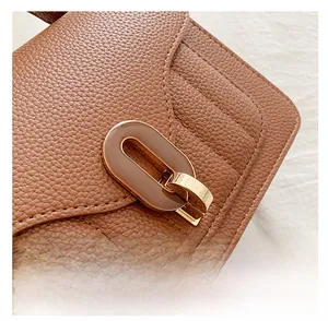Gros plan du sac en cuir grainé marron avec fermoir doré ovale et surpiqûres en V