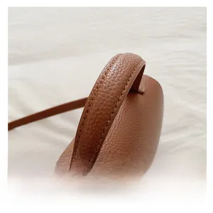 Vue détaillée d'un sac en cuir marron montrant la poignée supérieure et les surpiqûres
