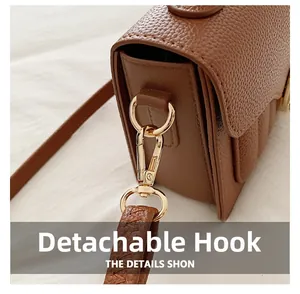 Détail de l'anneau en D doré et du crochet amovible sur un sac à main en cuir marron