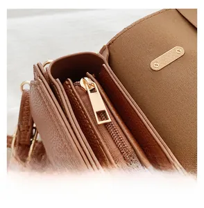 Détail macro du sac en cuir marron avec fermeture éclair dorée et compartiments internes