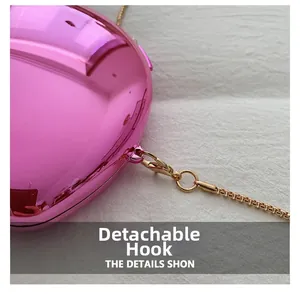 Macro detail of the detachable gold chain hook on a pink metallic mirrored clutch bag