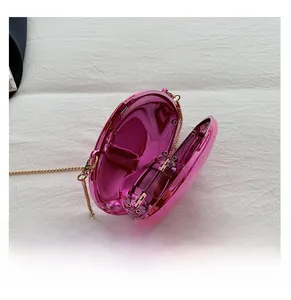 Detail view of oval metallic fuchsia hard-shell evening bag with gold chain strap