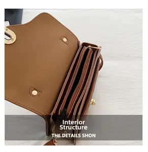 Détail macro du sac bandoulière en cuir marron avec trois compartiments et fermoir doré