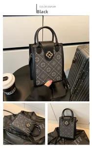 Close-up of black square crossbody bag with grey monogram print and gold clover clasp