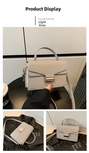 Detail of light grey textured leather handbag with gold metal clasp and top handle