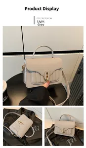 Détail du sac à main gris clair en cuir grainé avec fermoir doré et coutures verticales