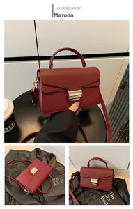 Detail of burgundy lychee leather handbag featuring gold metal buckle and top handle