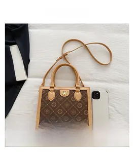 Detailed view of brown monogram tote bag with metal twist lock and smartphone for scale