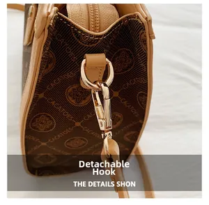 Détail du crochet métallique doré amovible et du motif logo sur le sac à main marron
