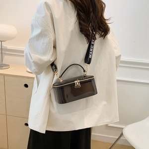 Black glossy patent leather box bag with lettered wide strap and gold hardware accents