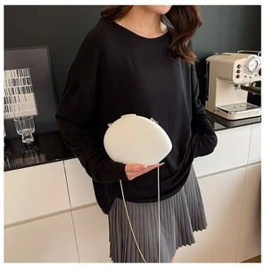 Chic white pebble evening bag with gold chain strap shown on model in modern setting