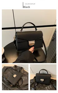 Detail of black lychee grain leather handbag with gold square clasp and shoulder strap