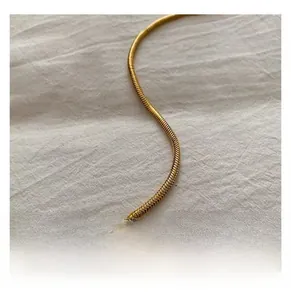 Détail macro d'une bandoulière en chaîne serpent dorée à la texture métallique lisse