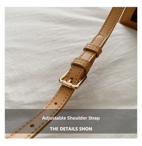 Close-up of adjustable light brown faux leather shoulder strap with gold metal buckle