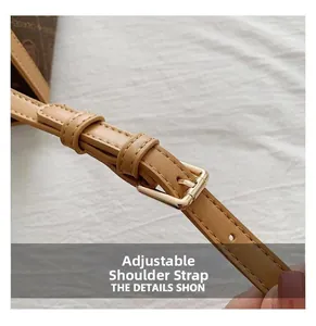 Close-up of adjustable brown leather shoulder strap with gold buckle on a tote bag