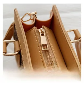 Detailed close-up of smooth golden metal zipper and retro monogram pattern on leather handbag