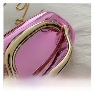 Détail d'une pochette en acrylique rose brillant avec poignée dorée et chaîne